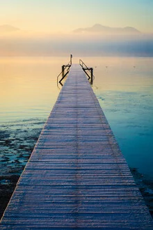 Charming jetty at Chiemsee during sunrise, surrounded by mountains.