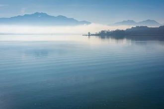 Winter landscape at Lake Chiemsee, calm atmosphere with fog over the water