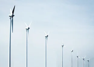 Photo art by Violeta Stanojevic: Wind turbines against a blue sky with soft clouds