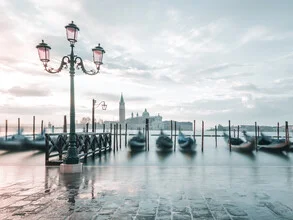 Soft pastel colors depict the sunrise over Venice with gondolas in the water.
