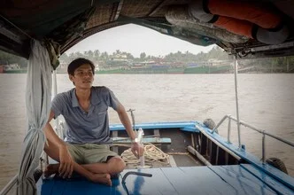 Captain in the Mekong Delta: serene scene with a traditional boat and lush surroundings.