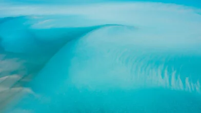 Fotografie einer blauen Welle, die sanft das Wasser umspielt, in ruhiger Atmosphäre.