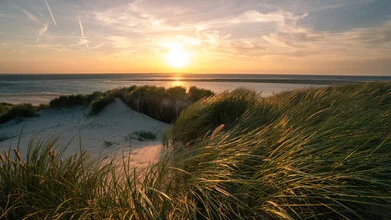 Dune view at the North Sea with gentle waves and a warm sunset