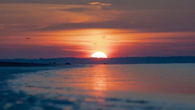 Sunset over the North Sea, gentle waves and warm colors in the evening sky.