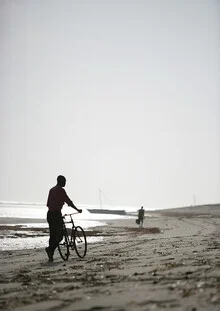 Junge auf einem Fahrrad am Strand mit sanften Wellen im Hintergrund
