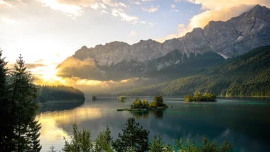 Photo art: Sunrise over a calm lake with mountains in the background.