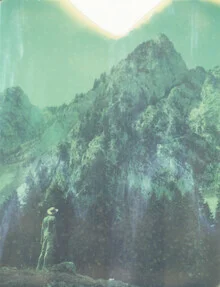 Photo art by Jennifer Rumbach: Man with hat in front of majestic mountains and fir trees.