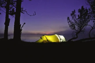 Glowing tent at night on a Norwegian island, warm light creating a cozy atmosphere.