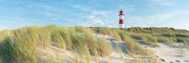Panoramic view of Sylt with a lighthouse in the foreground and gentle dune landscapes.