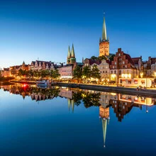 Night view of Lübeck featuring illuminated churches and the Trave river