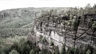 Verwunschene Landschaft des Elbsandsteingebirges mit sanften Hügeln und Bäumen.