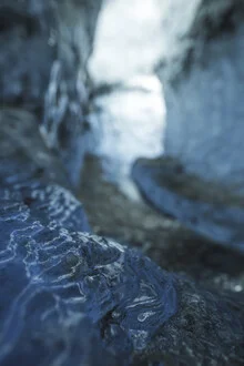 View inside an ice cave: cold blue ice formations with gentle light patterns