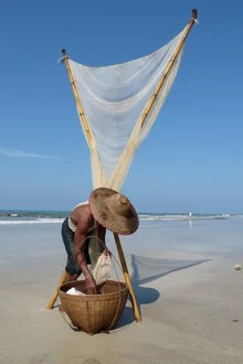 Fisher in Myanmar at the beach with a hat and net in a calm scene