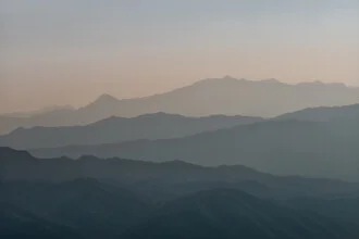 Fotokunst: Schichten von Bergen bei Sonnenuntergang, warmes Licht und ruhige Stimmung.
