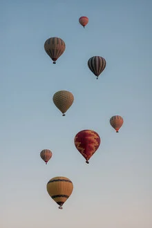 Colorful hot air balloons float peacefully over the Turkish landscape.