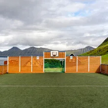 Photo featuring artificial grass, wood wall, and a tranquil island in the Faroe Islands.
