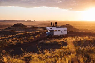 Family on a truck at sunrise, relaxed mood in nature.
