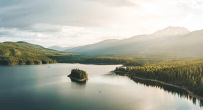 Kayak on a calm lake surrounded by green trees and mountains, evoking a peaceful holiday mood.