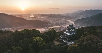 Photo art of a Japanese castle on a mountain, surrounded by gentle forests.