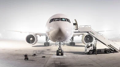 Fotokunst von Inflight Galerie: weißes Flugzeug am Himmel über einem Flughafen.