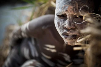 Photo art of a Suri boy by the river, adorned with traditional makeup