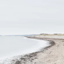 Photographic depiction of a calm beach landscape with fog and gentle waves.