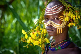 Portrait of a Suri woman in her natural surroundings, warm light and vibrant colors.