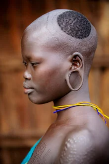Portrait of a woman in Suri style showcasing traditional hairstyles in a calm setting.