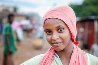 Photo art by Miro May: Woman in a village, observing everyday life with a smile.