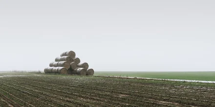 Hay bale on a field, surrounded by gentle hills and fog, calm rural scene.