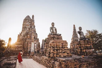Woman in a red dress in front of a temple in Thailand during sunset