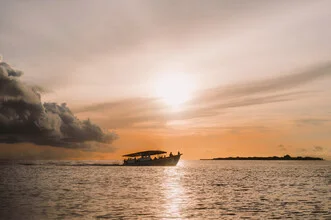Sunset in the Maldives with orange clouds and calm ocean waters
