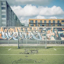 Fotokunst von Franz Sussbauer: Graffiti an einem Bolzplatz mit Kunstrasen und Sichtschutzzaun